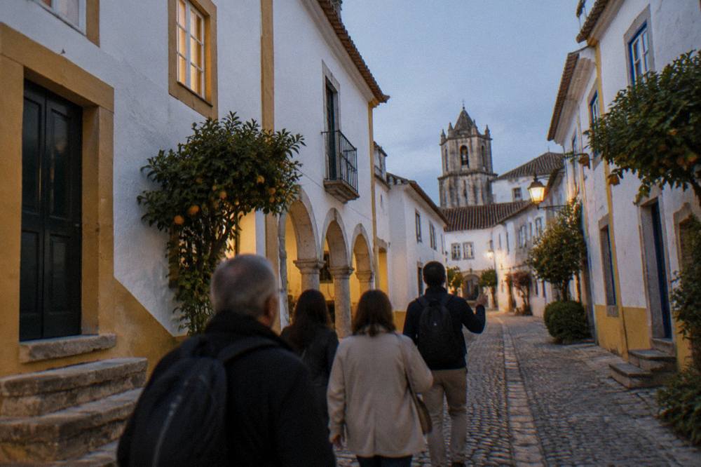 A small group following a guide through a narrow evening street in Évora