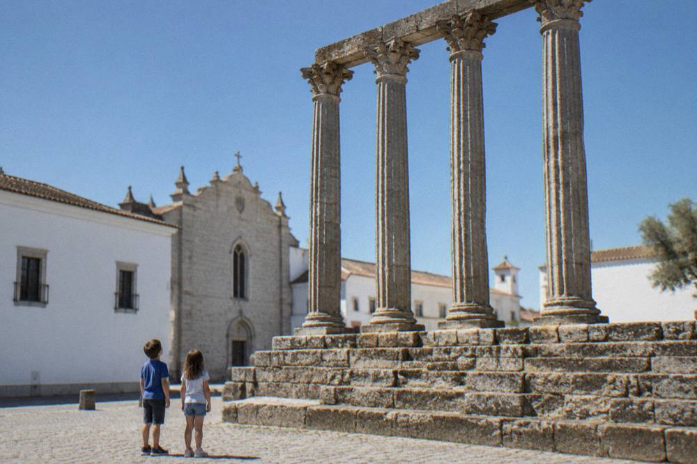 Children looking up at the tall Roman columns of the Templo Romano in Évora