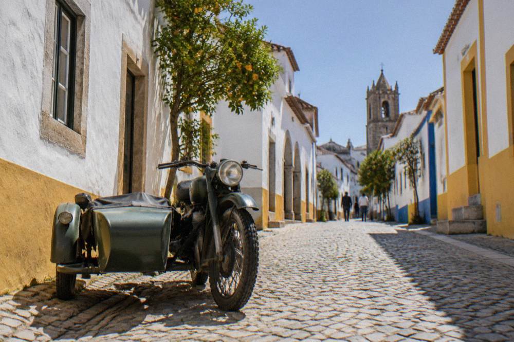 A vintage motorcycle sidecar parked on a cobbled street in medieval Évora