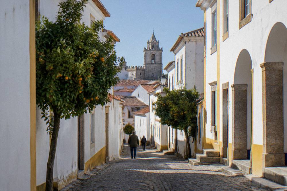 A whitewashed Alentejo hill town with a castle tower rising above red rooftops