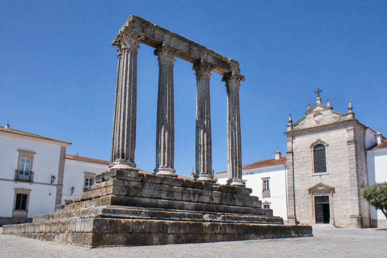 The Roman temple of Évora standing in an open square under a clear sky with whitewashed buildings behind it