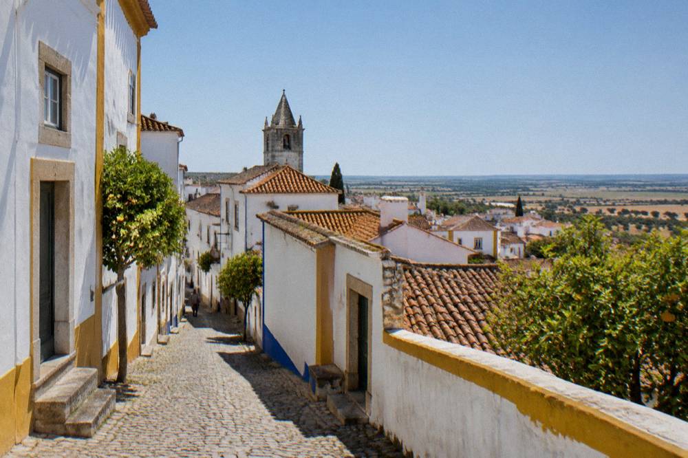 Red tiled rooftops of Évora seen from outside the old city walls under a wide sky