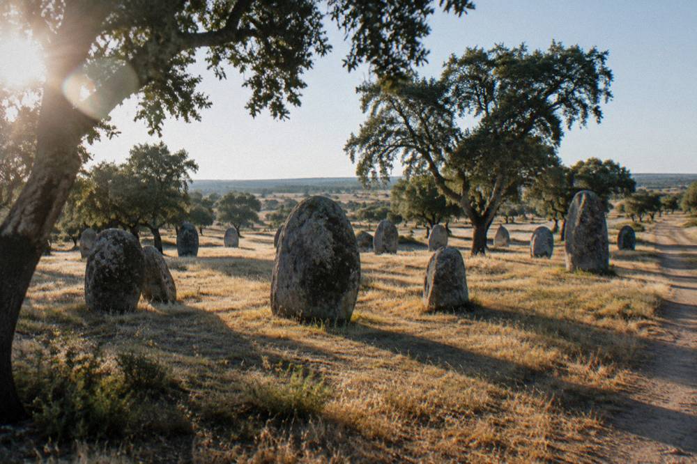 Standing stones of the Almendres cromlech on a grassy hillside in the Alentejo countryside