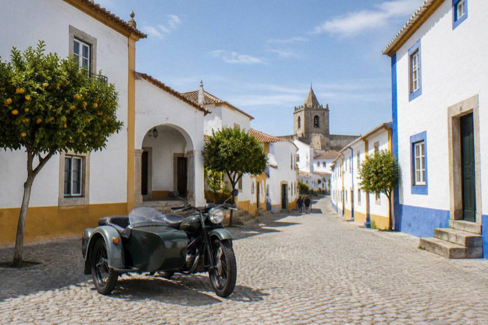 Classic motorcycle sidecar parked on a cobbled square in Évora
