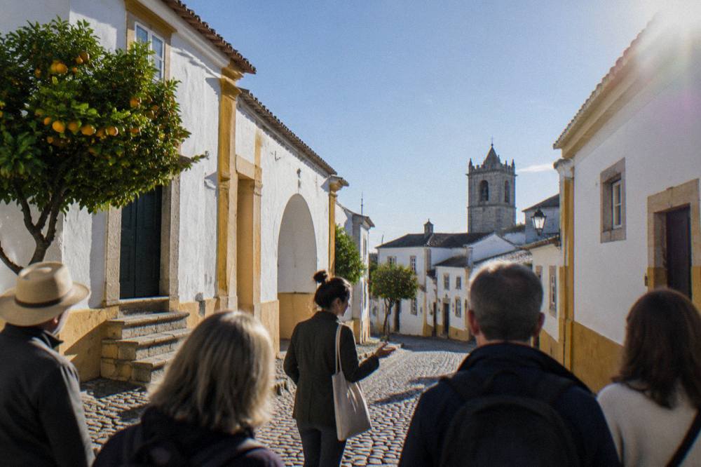 A guide leading a small group of visitors through a cobbled Évora street