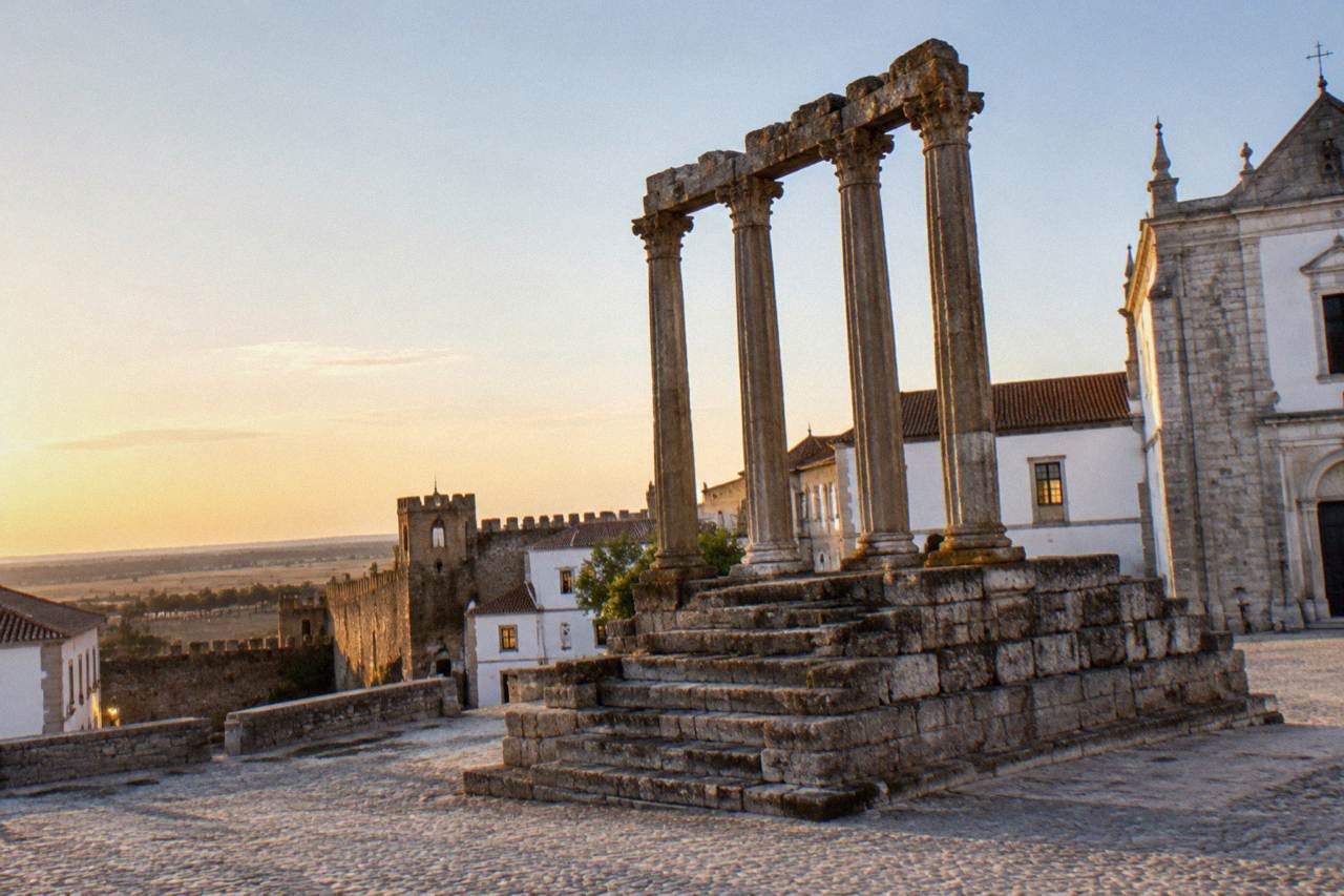 The Roman temple and old town walls of Évora seen in warm evening light