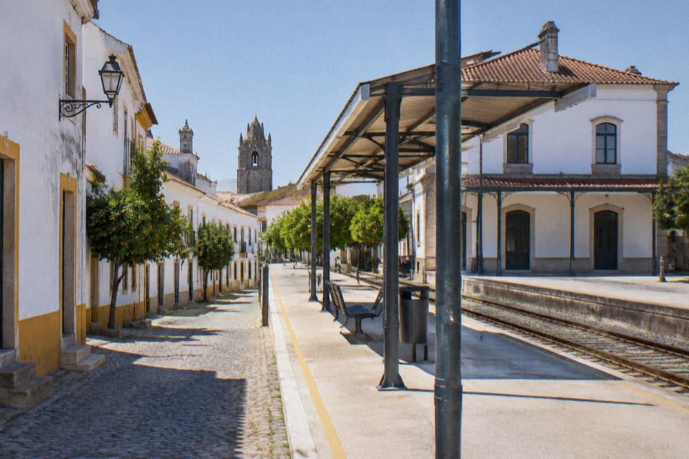 A train platform at Évora station with the station building behind it