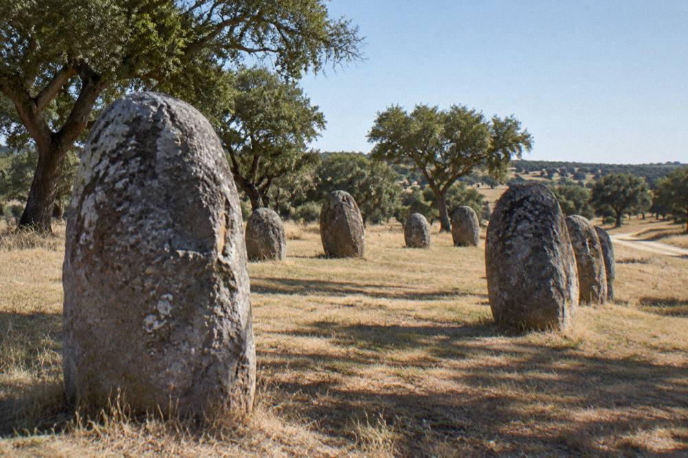 Standing stones of the Almendres cromlech on a grassy slope in the Alentejo countryside