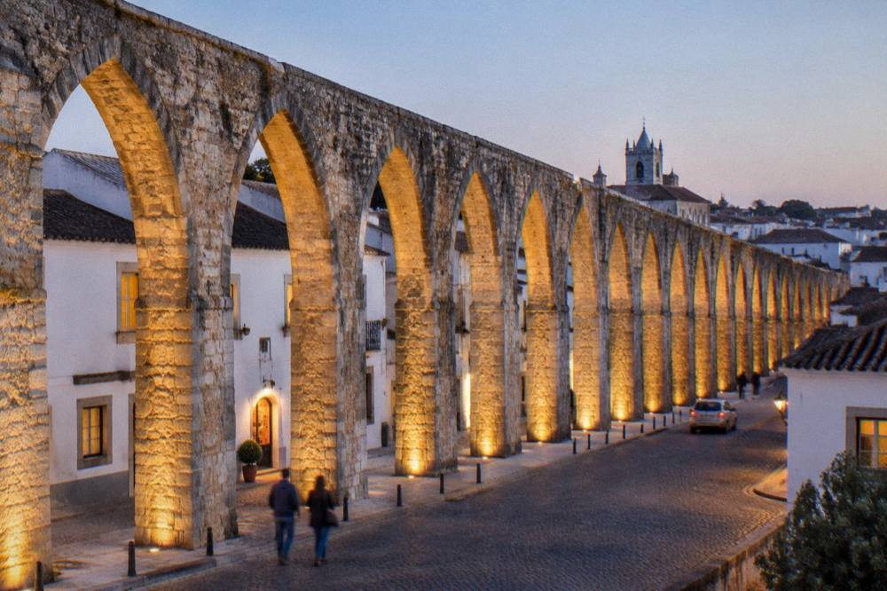 The illuminated aqueduct arches of the Água de Prata entering Évora at dusk