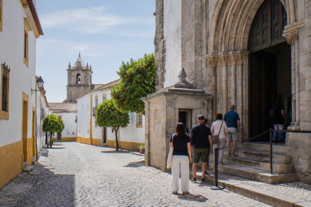 A stone ticket counter and entrance of a historic Portuguese church with a small queue of visitors
