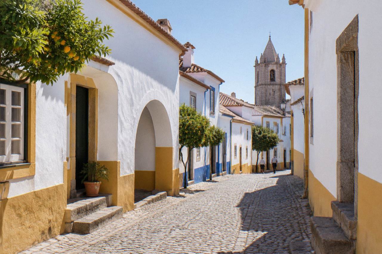 An empty road crossing the rolling Alentejo plain toward Évora under a wide sky