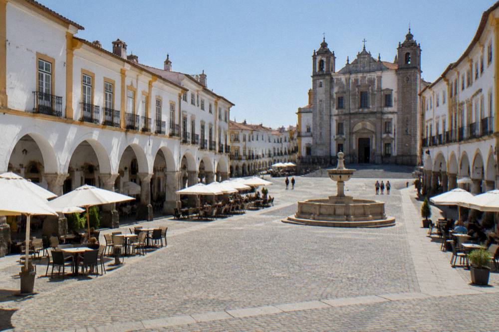 Arcaded square of Praça do Giraldo in Évora with cafés under white arches