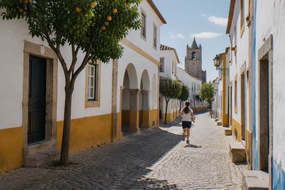 A quiet Alentejo road lined with cork oaks running toward the horizon