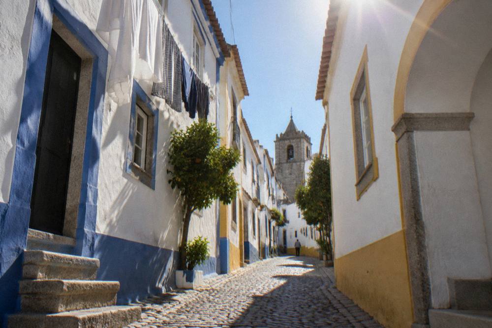 A narrow whitewashed street in Évora with blue and yellow trim and hanging laundry