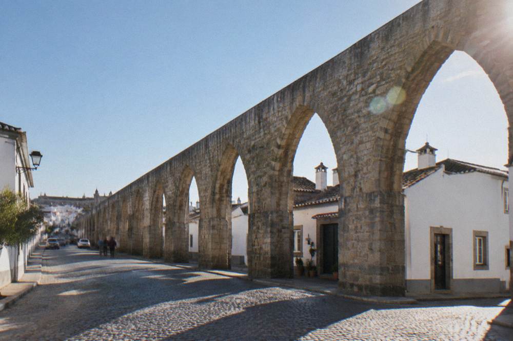 Arches of the Água de Prata aqueduct running through a street on the edge of Évora