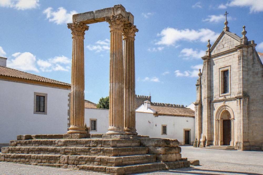 Golden stone columns of the Roman temple in Évora rising above a quiet square
