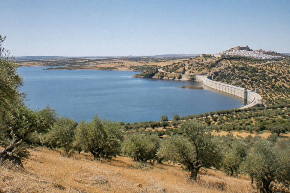 White hilltop village of Monsaraz above the wide Alqueva reservoir at golden hour
