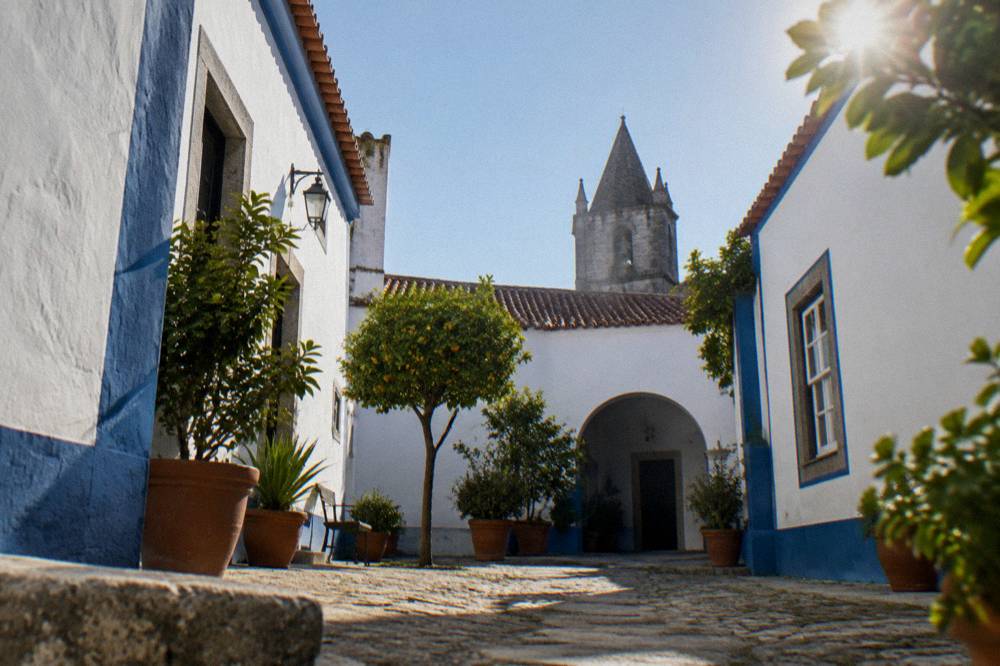 A hotel courtyard in Évora with whitewashed walls, blue trim and potted plants