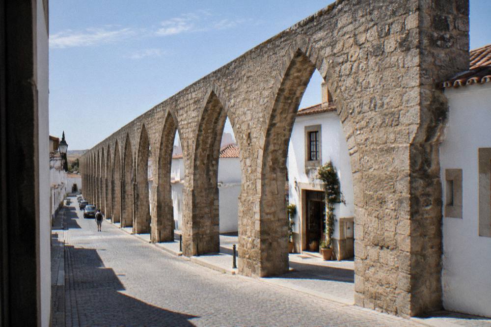The stone arches of the Água de Prata aqueduct running through a residential street in Évora