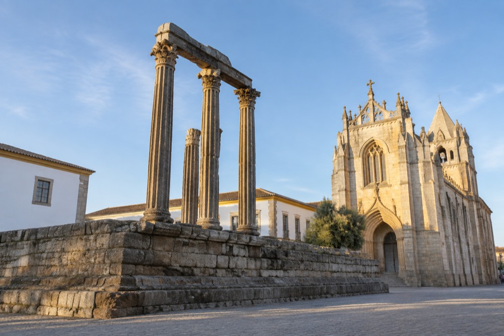 The Roman temple columns of Évora standing beside the cathedral at golden hour
