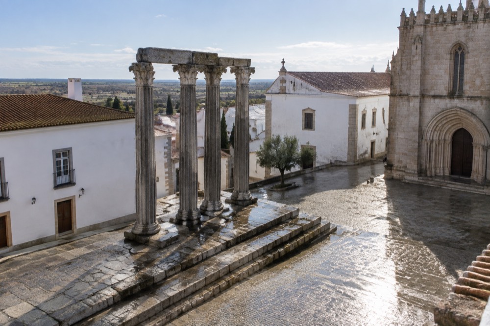 Roman temple columns rising beside later buildings in central Évora