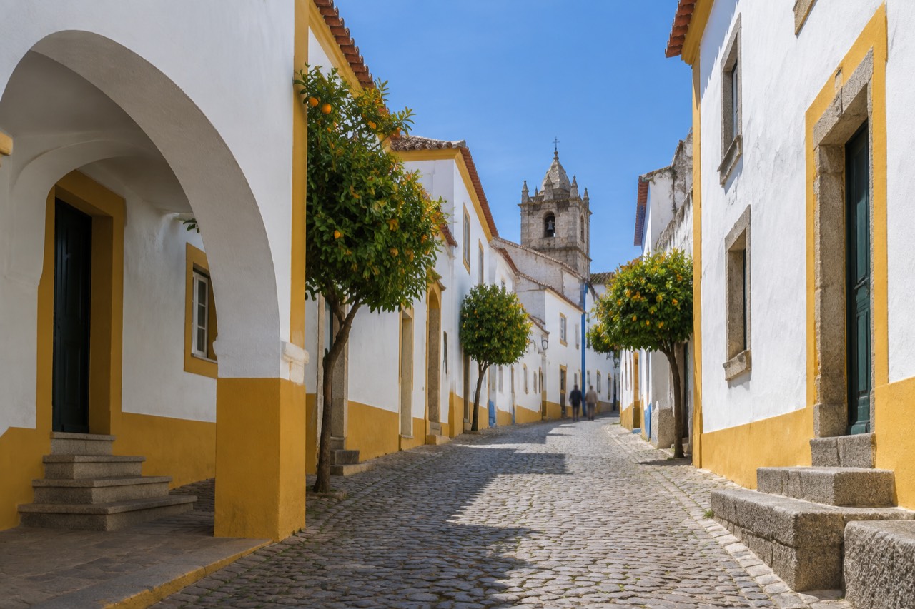 A quiet street of whitewashed houses with yellow trim inside the historic centre of Évora