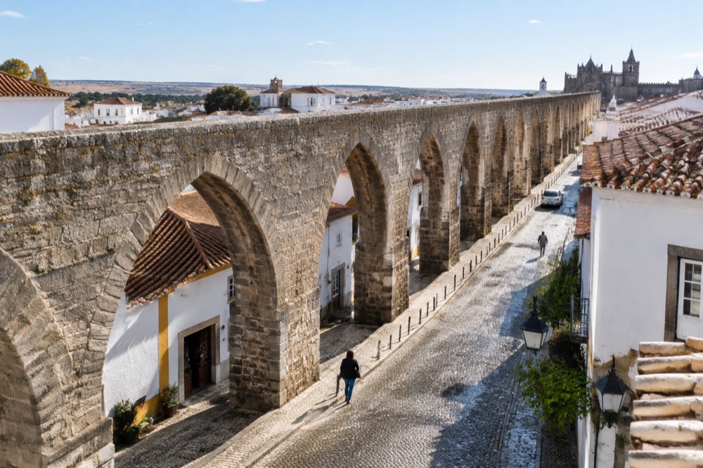 The stone arches of the Água de Prata aqueduct running along a street on the edge of central Évora