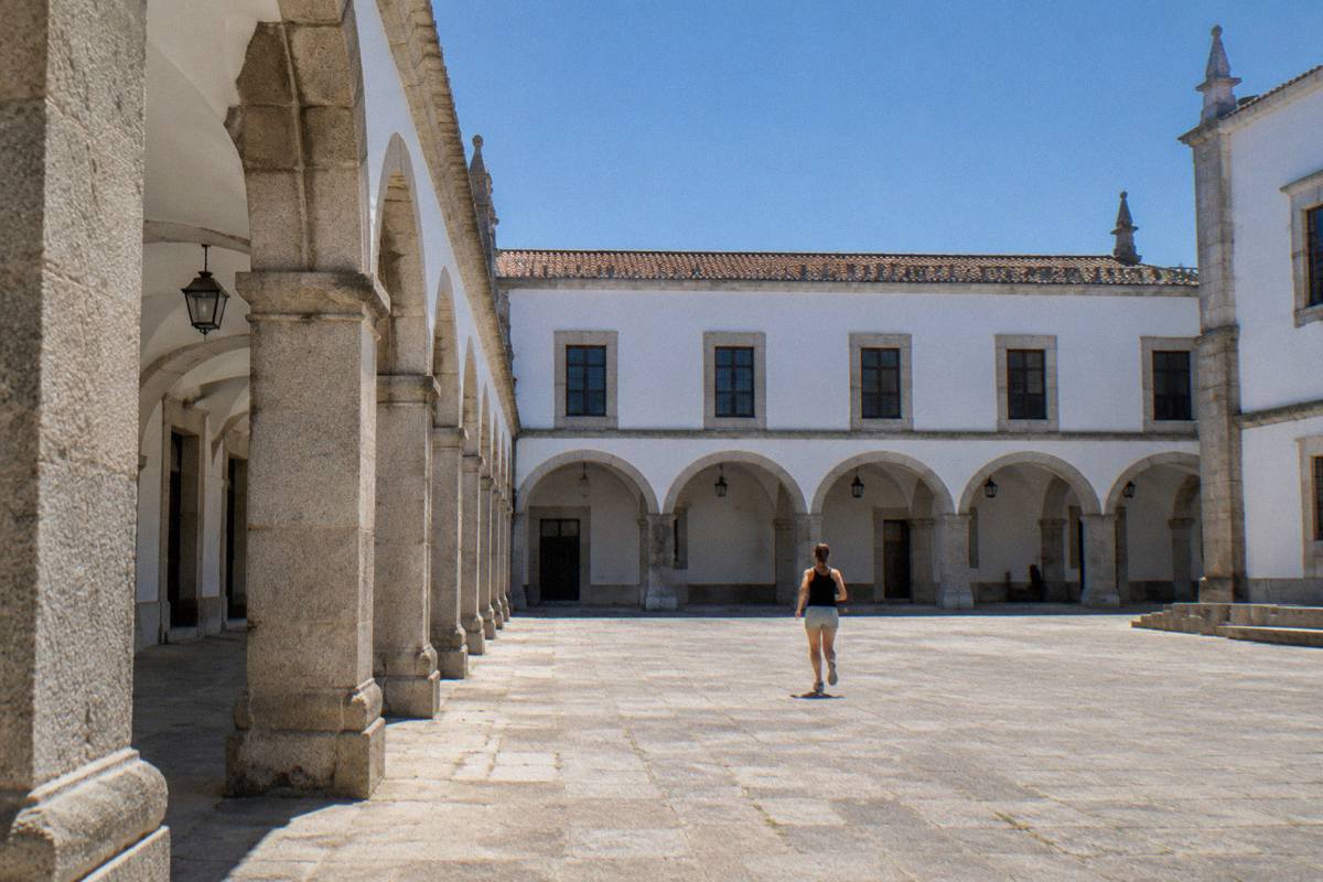 A pale granite palace with a deep arcaded courtyard under a low grey sky with shining wet paving