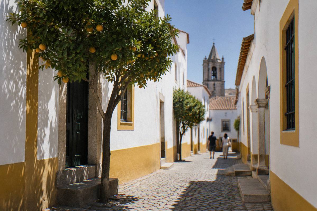 Narrow pedestrian lanes of whitewashed houses trimmed in ochre with a granite church tower glimpsed ahead