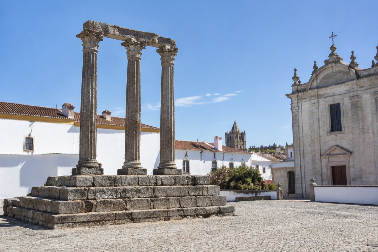 The Roman temple columns rising above the rooftops of Évora's historic centre in warm afternoon light