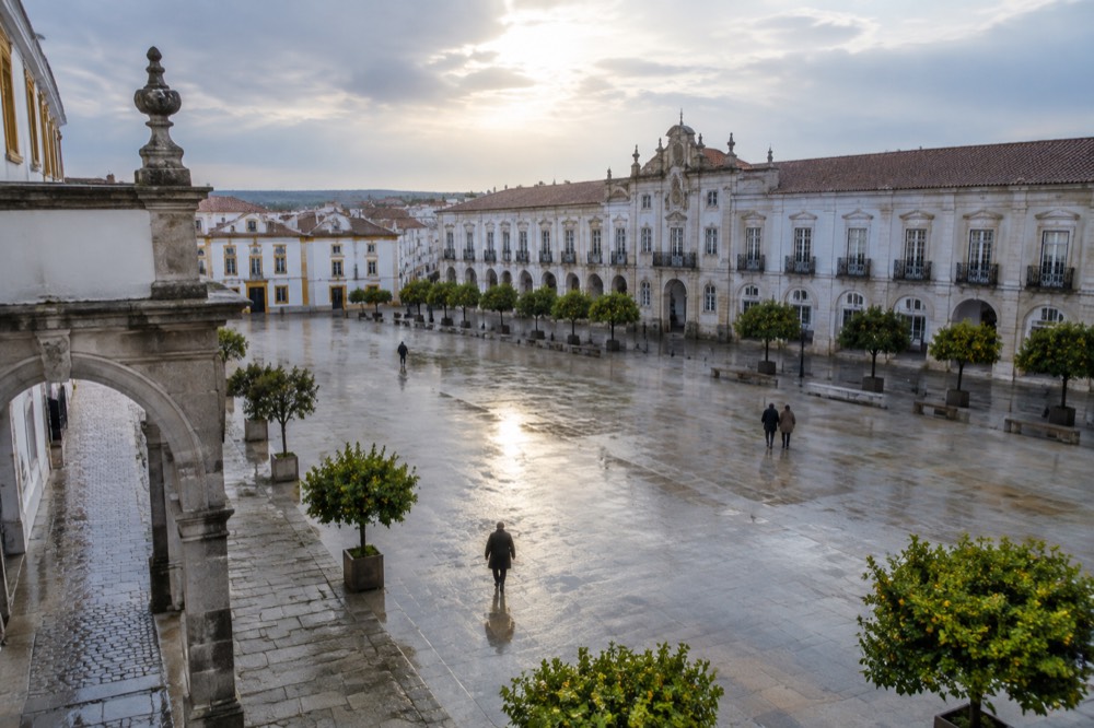 Marble archway and wet stone pavement in Vila Viçosa under grey light