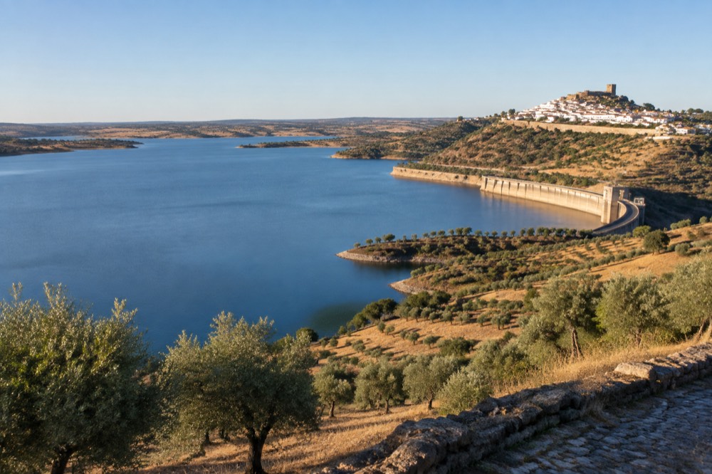 The white hilltop village of Monsaraz above the Alqueva lake at golden hour.