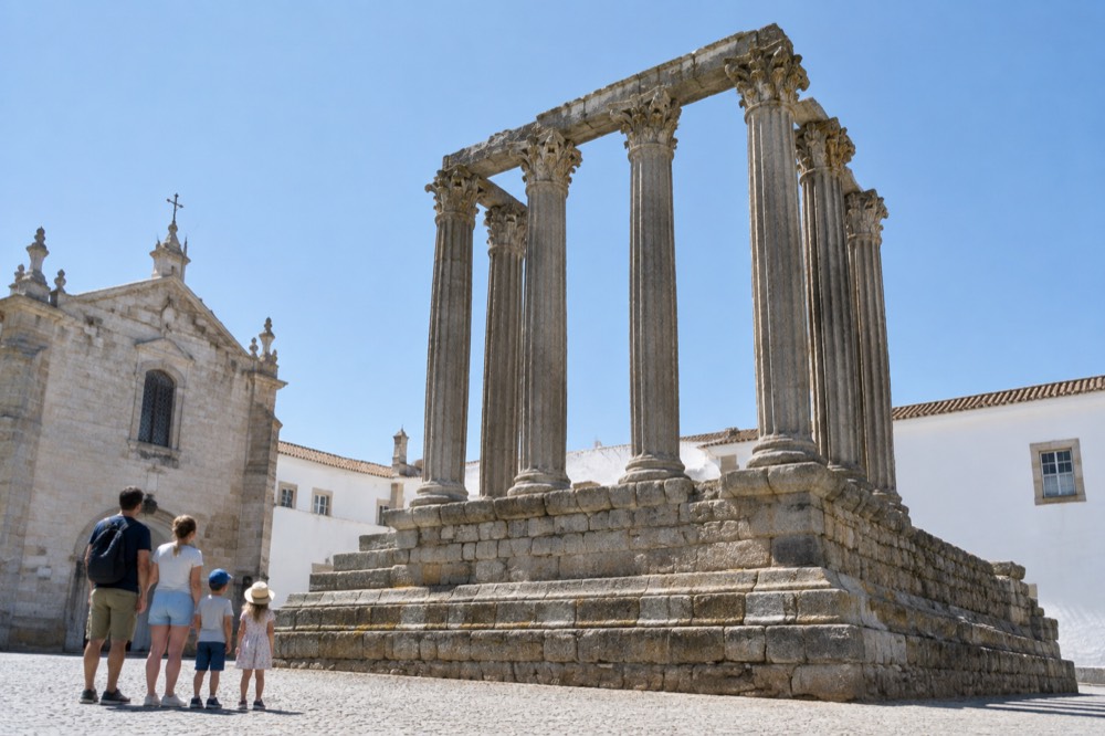 A family with children looking up at the columns of the Roman temple in Évora