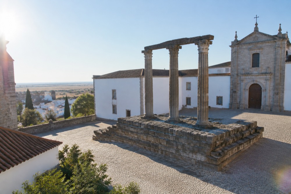 Ancient Roman columns of the Templo Romano in Évora framed by whitewashed buildings