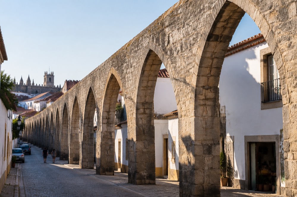 The stone arches of the Água de Prata aqueduct passing between houses in Évora